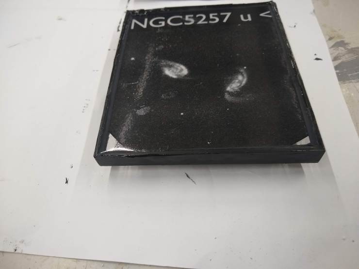 A model of NGC5257 with the galaxy image embedded inside the resin. The edges of the model have been panted black.